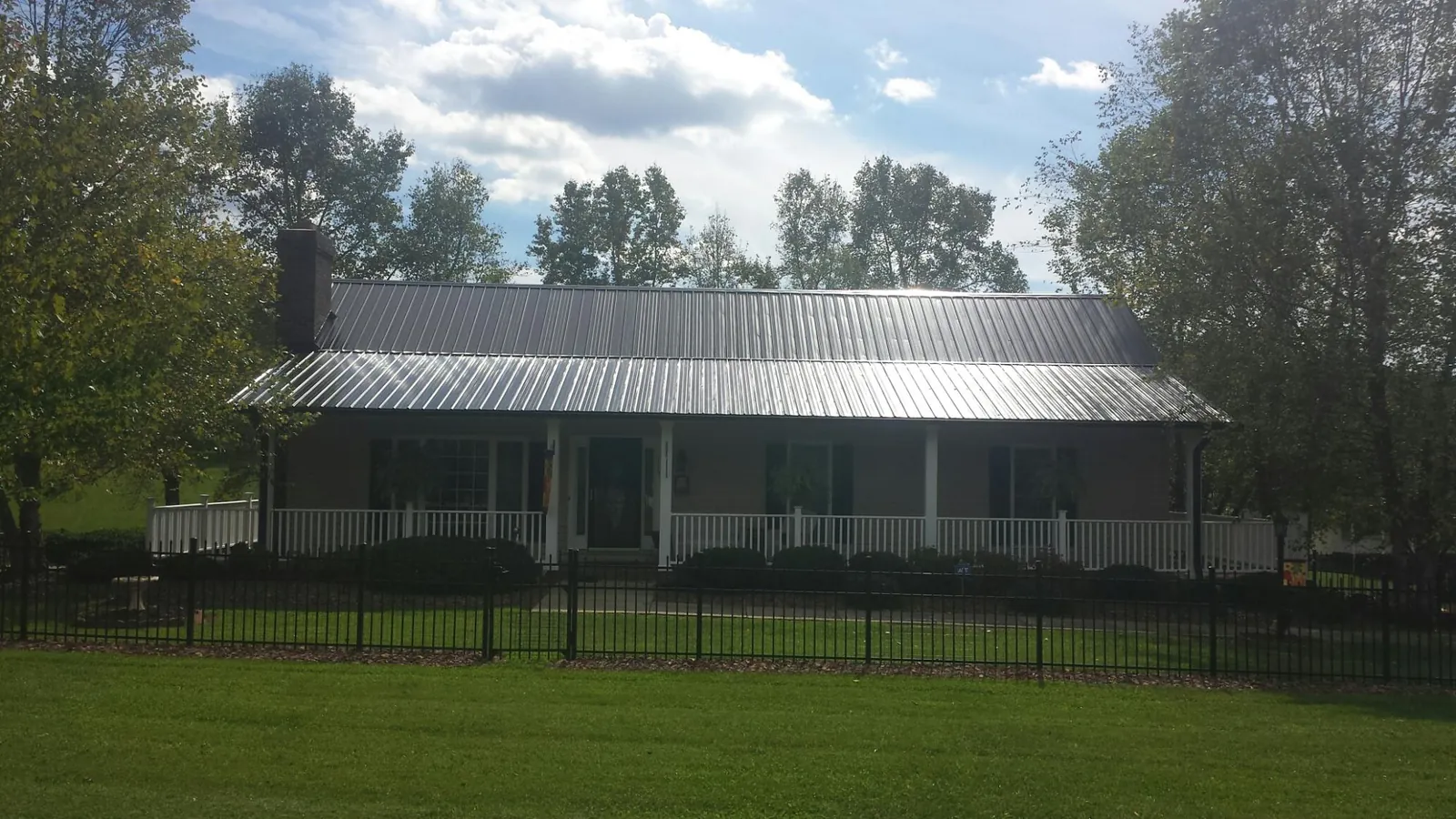 Gray metal roof on a brick ranch with a full width front porch — Gutter Guard Installation work by our crew in Uniondale