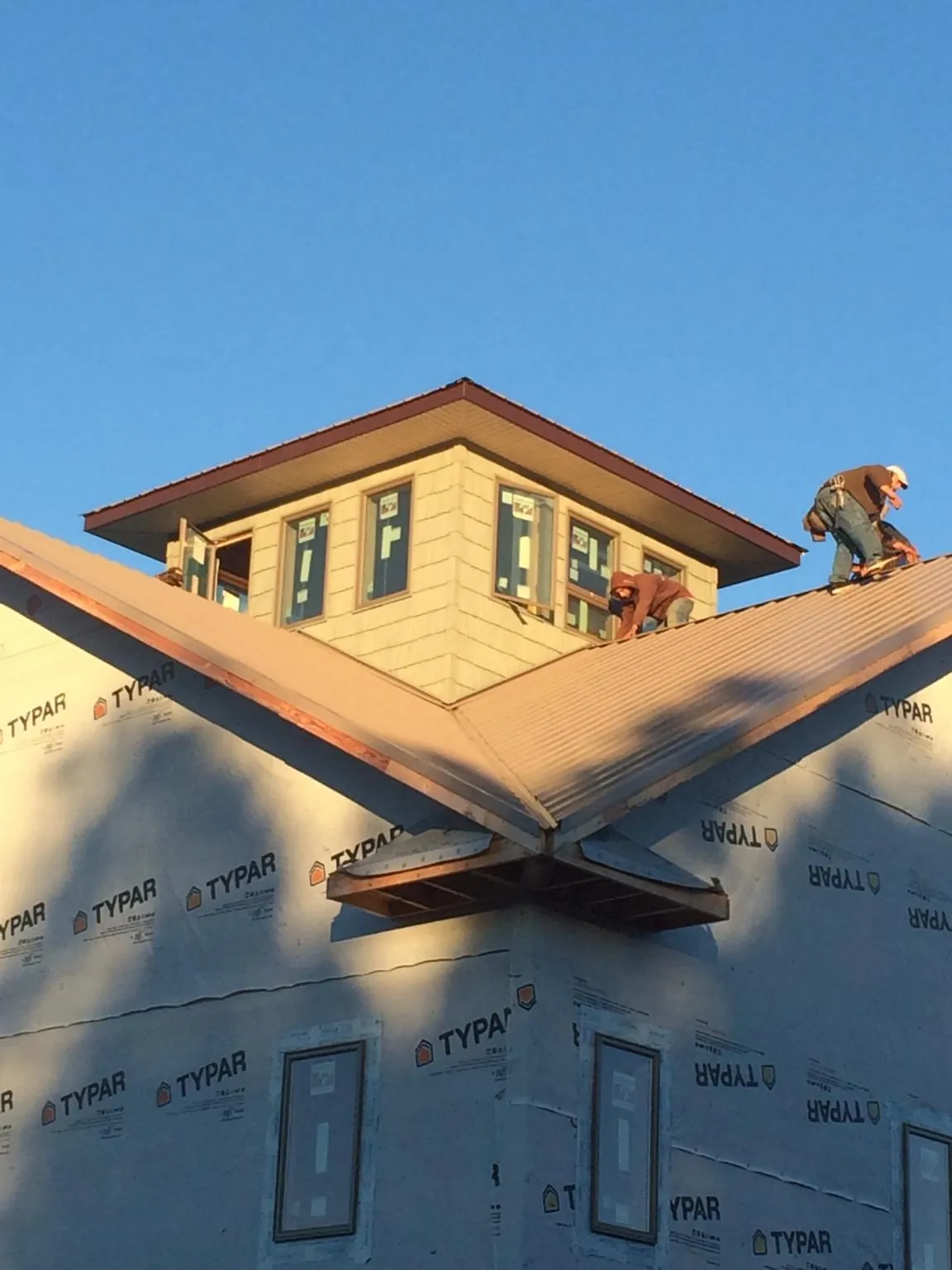 Roofers working around a rooftop cupola on a new metal roof at sunset — Roof Waterproofing in Uniondale by Roofing Brothers